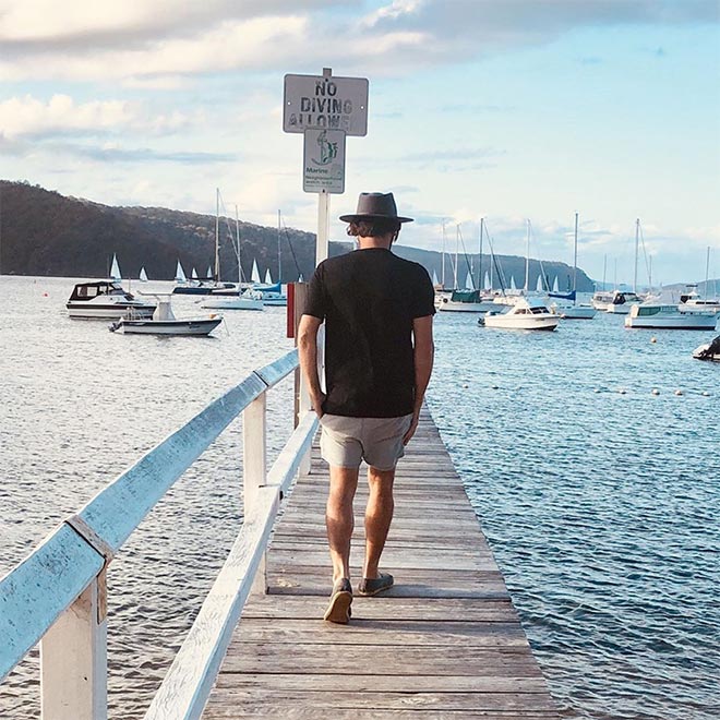 Man walking along a jetty wearing a black icebreaker Tech Lite t-shirt