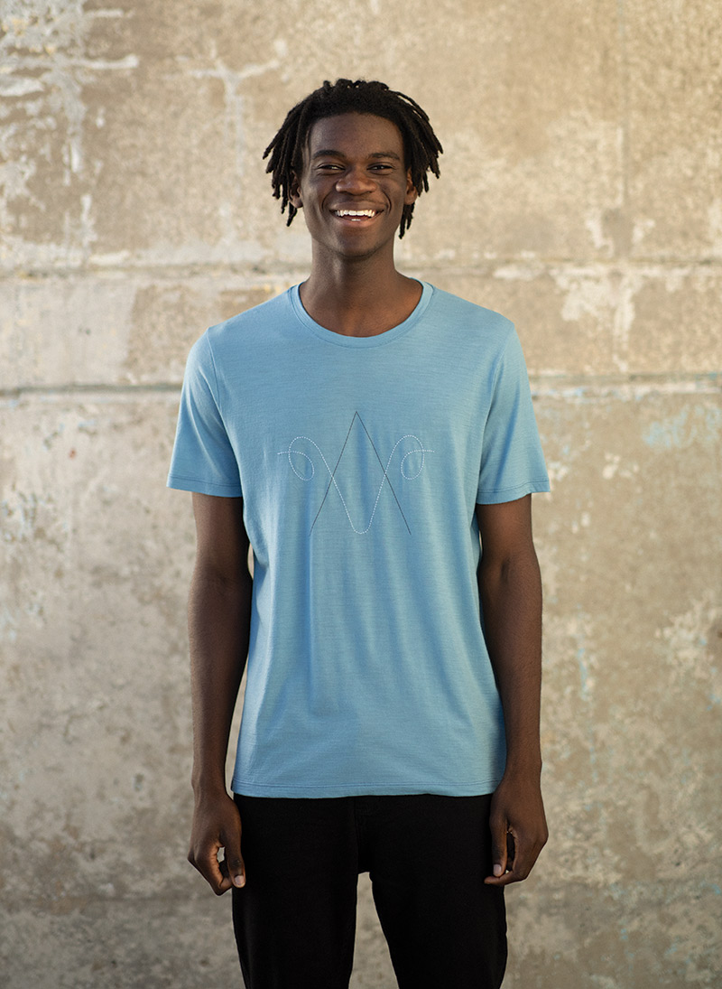 Man standing outside on city street wearing the blue icebreaker XXV collection t-shirt.