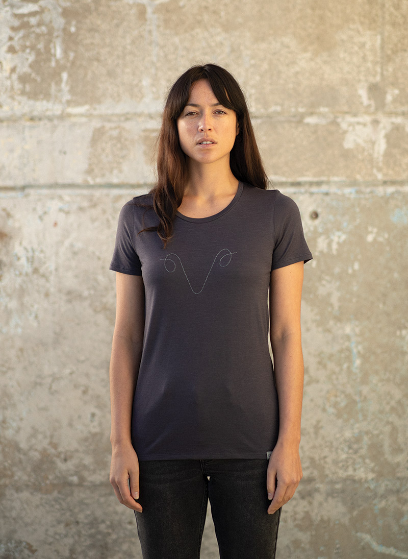 Woman standing in front of cement wall wearing the icebreaker XXV collection t-shirt.
