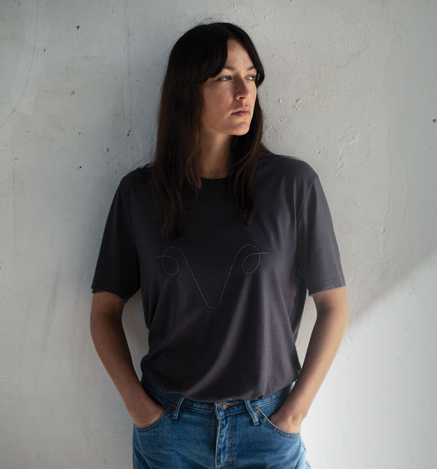 Woman standing in front of cement wall wearing the icebreaker XXV collection t-shirt.