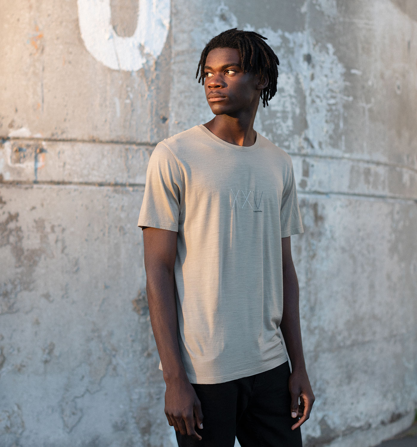 Man standing outside on city street wearing the tan icebreaker XXV collection t-shirt.