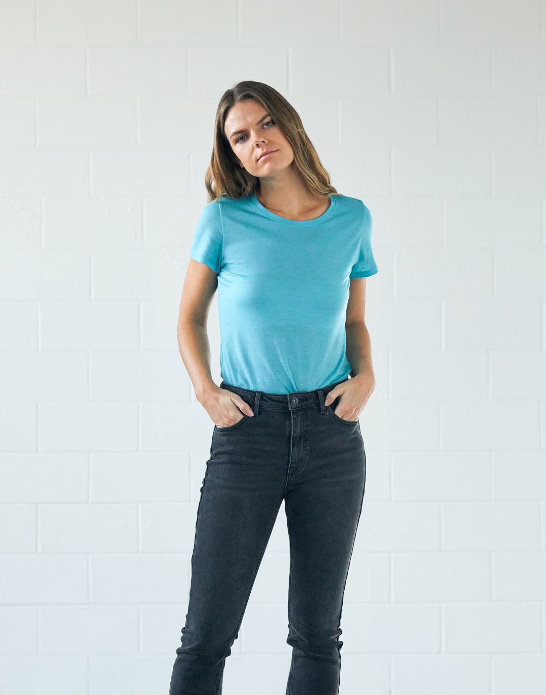 Une femme qui porte un t-shirt cyan et un jean gris foncé